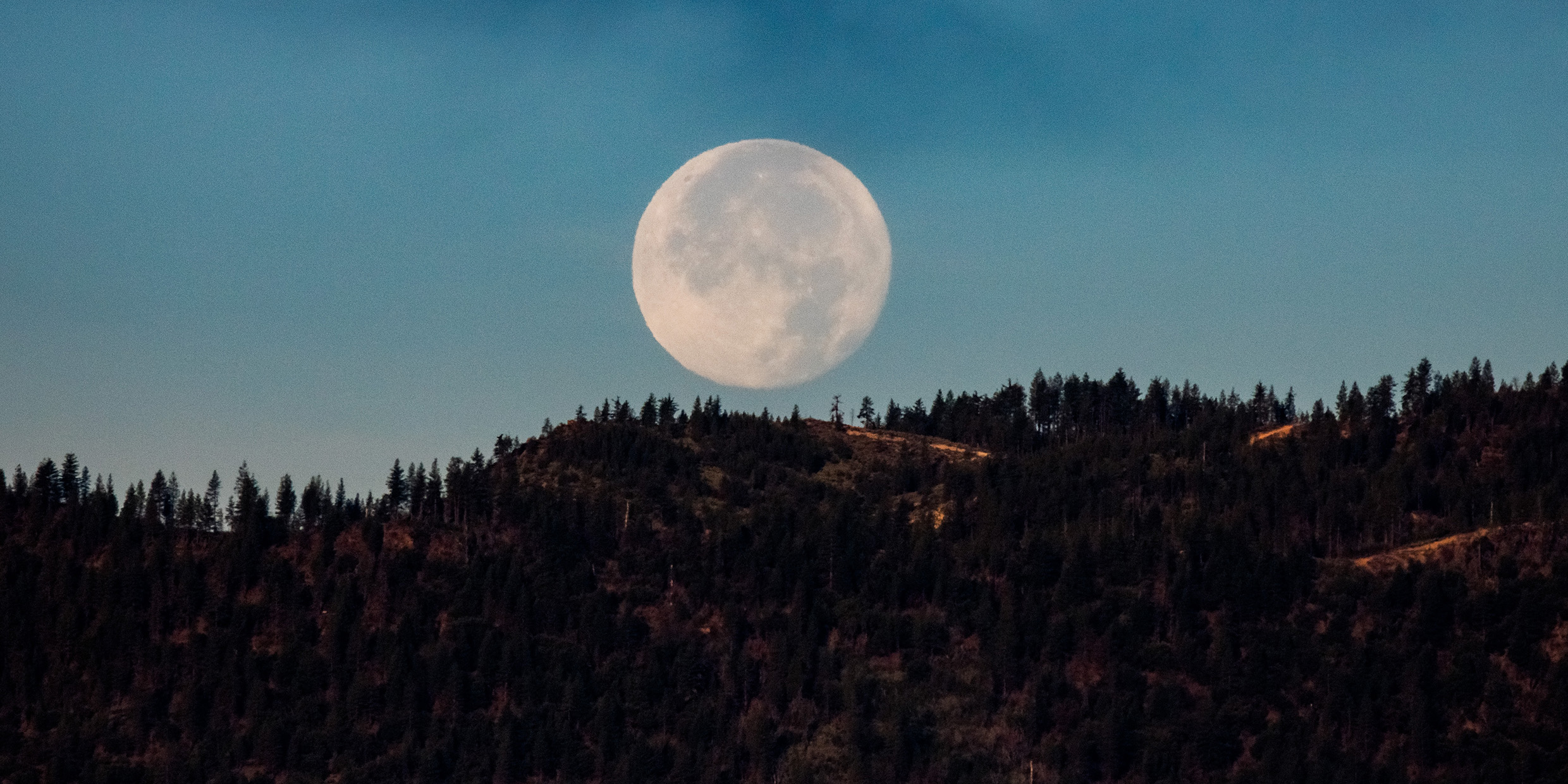 Image of the moon rising over hill