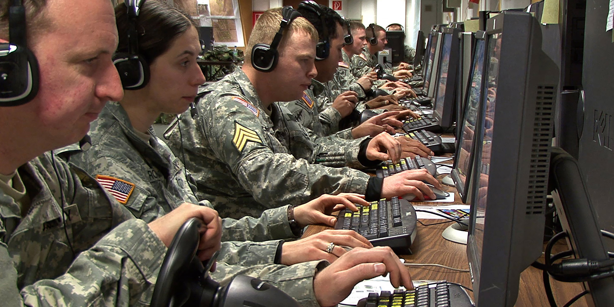 Image of a squad of soldiers lined up behind computer terminals