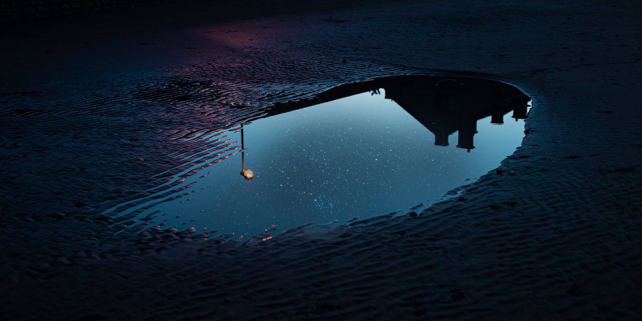 Image of a puddle of water reflecting the night sky