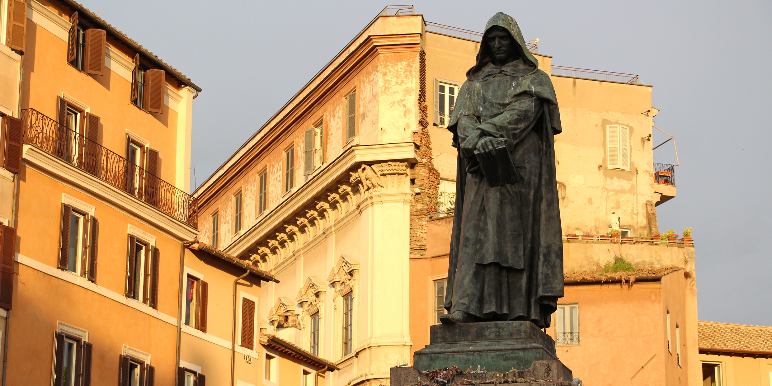 Photo of a statue of a man in a hooded cloak holding a book