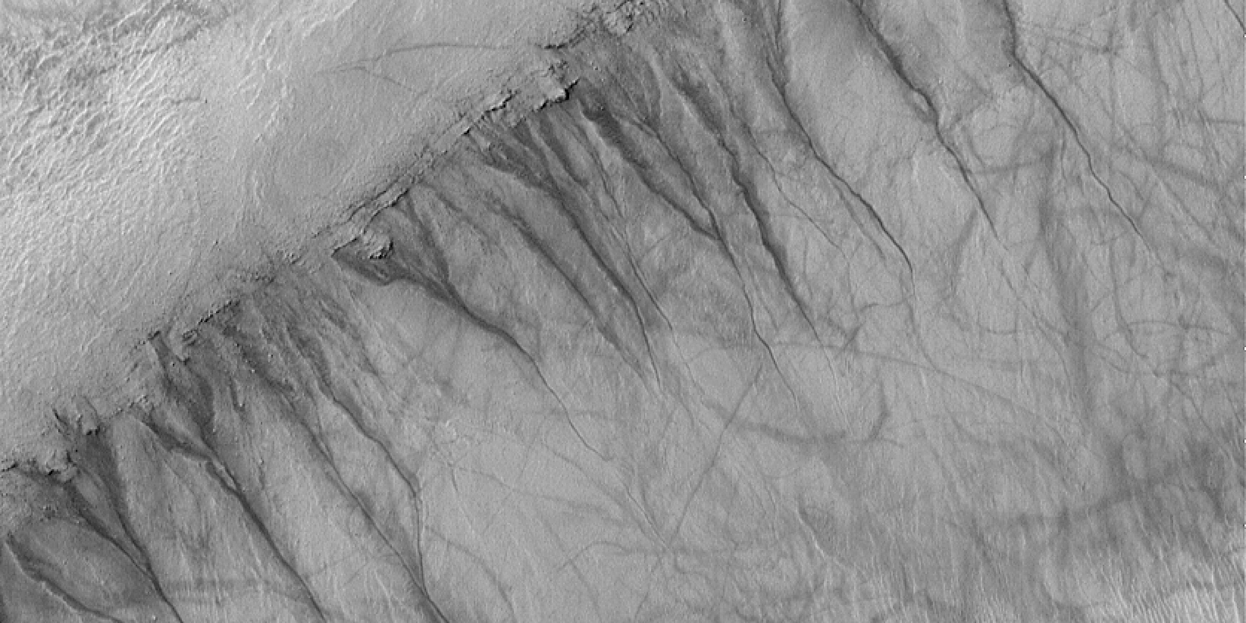 Satellite image of dark streaks running down sides of crater wall on surface of Mars