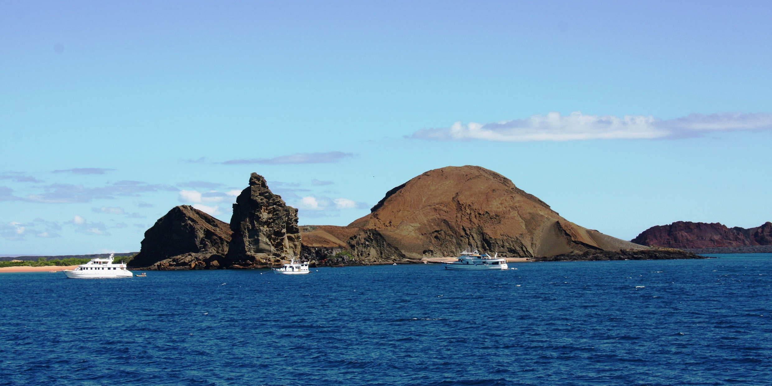 Image of a rocky island with several recreational boats offshore