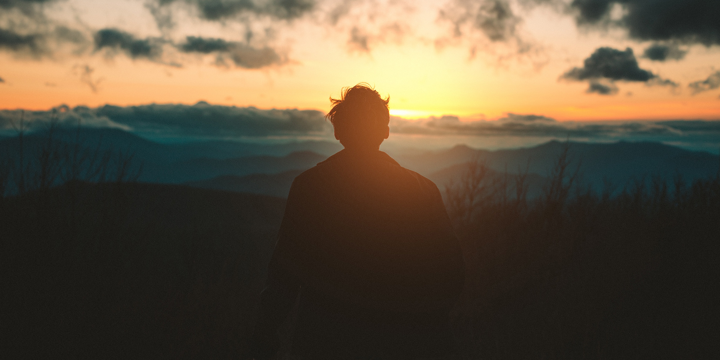 Image of a man in silhouette observing the sunrise