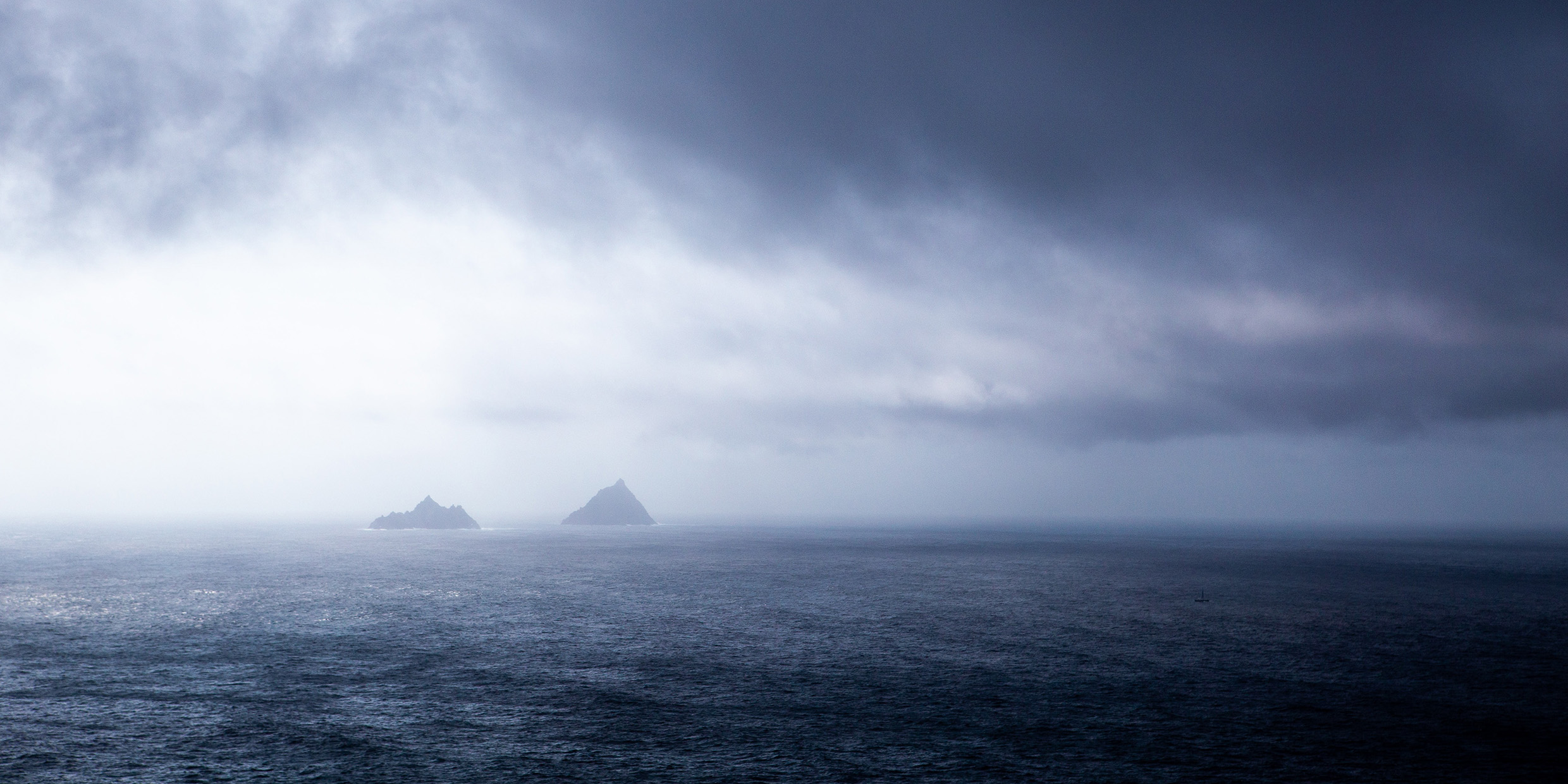 Image of two jagged windswept islands in a wide, dark ocean